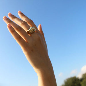 Model wearing gold dome ring with ridged texture on finger.