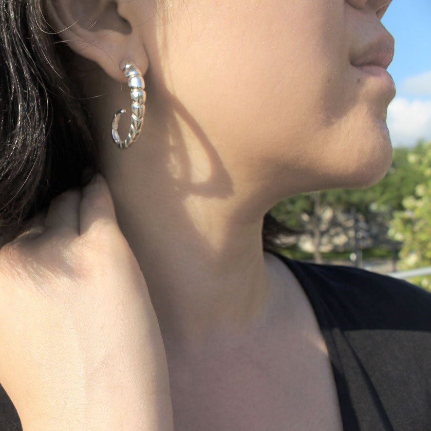 Model wearing sterling silver earring with ridged texture.