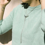 Model wearing crescent shaped pendant on silver chain necklace.