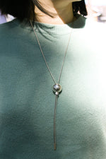 Model wearing sphere shaped pendant on silver chain necklace.