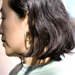 Side view of model wearing silver earring with ridged texture.