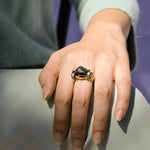 Model wearing gold brass ring on finger.